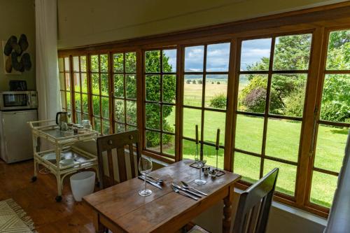 a dining room with a table and a large window at Tafeni Farm Cottages in Swartberg