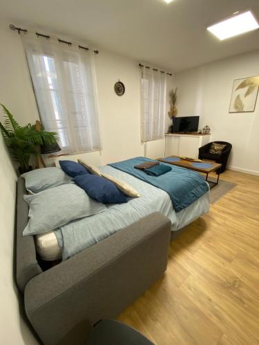 um quarto com uma cama com almofadas azuis e um sofá em Studio Cléo em Montauban