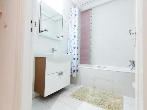 a bathroom with a sink and a tub and a mirror at Holidays HOUSE in La Marsa