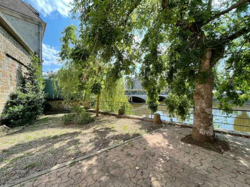 un árbol en un patio al lado de un edificio en Les Maisons d'Auré: Le studio en Putanges