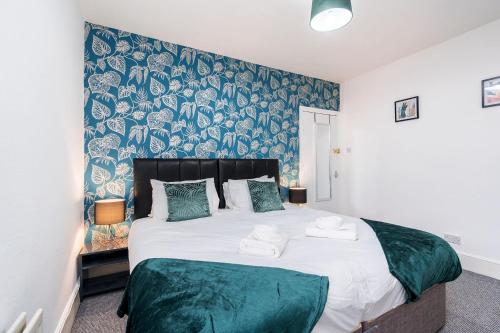 a bedroom with a large bed with green and blue wallpaper at Four Bedroom City Centre Large Derby House Contractors Leisure in Derby
