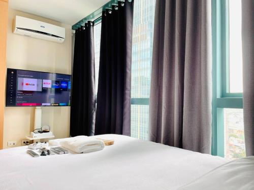 a bedroom with a white bed and a window at Thompson Suites - 2 beds, One Uptown Residences 28F A - XBOX & Netflix in Manila
