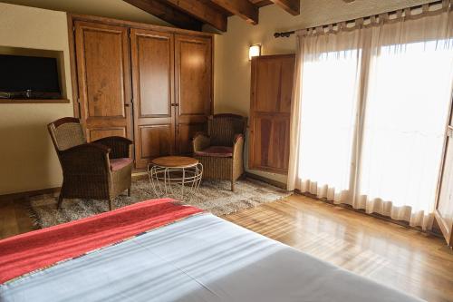 a bedroom with a bed and chairs and a tv at Cal Marrufès in Puigcerdà