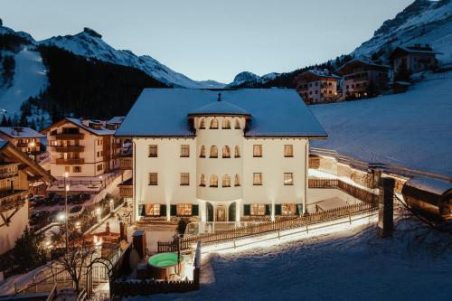 a large building with snow on the ground at Hotel Alpenrose in Arabba
