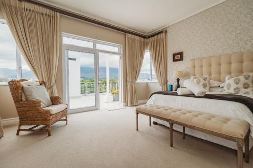 a bedroom with a bed and a chair and a window at White House on Kingswood Golf Estate in George