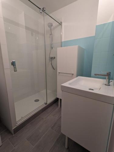 une salle de bain blanche avec une douche et un lavabo dans l'établissement Coquet appartement à 300 m du port du Pouliguen, au Pouliguen