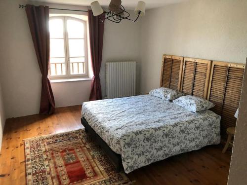 a bedroom with a bed and a large window at Maison Chez Jeannot in Saint-Geneys-près-Saint-Paulien