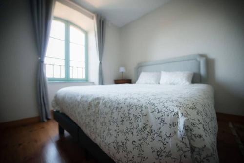 a bedroom with a bed with a flowered blanket and a window at Maison Chez Jeannot in Saint-Geneys-près-Saint-Paulien