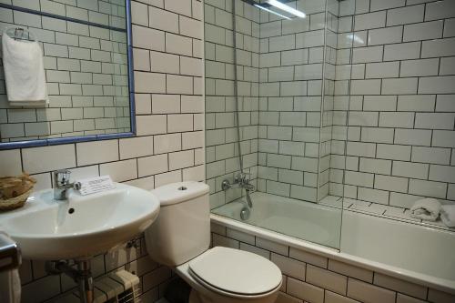 a bathroom with a toilet and a sink and a tub at Cal Marrufès in Puigcerdà