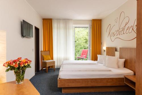 ein Hotelzimmer mit einem Bett und einer Vase aus Blumen in der Unterkunft EWERTS Hotel in Netphen