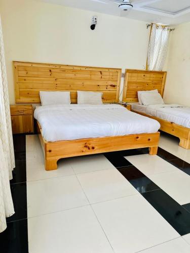 two beds in a room with wooden headboards at F R Darya e Swat Hotel in Swat