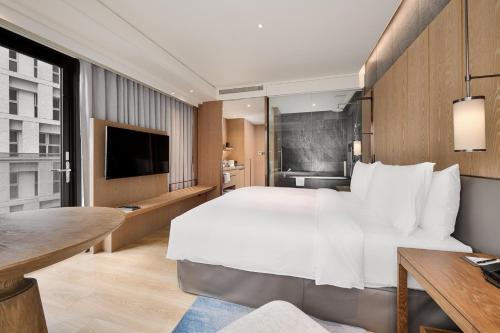 a hotel room with a large bed and a desk at DoubleTree by Hilton Taipei Zhongshan in Taipei