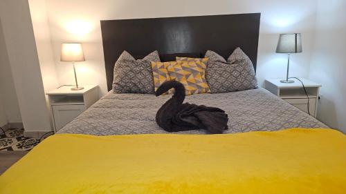 un cygne noir assis sur un lit avec deux lampes dans l'établissement La Pause Laurag-aise l'embleur Oc Keys 27, à Castelnaudary