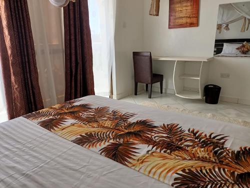 a bed with a comforter with a desk in a bedroom at Villa Becky - Diani Beach in Diani Beach