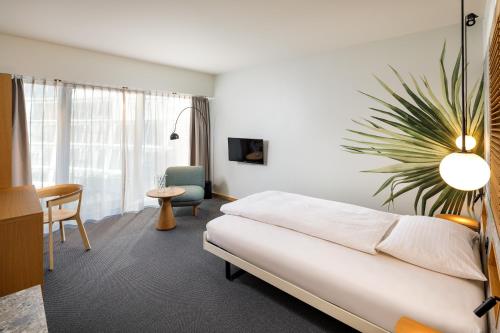 a hotel room with a couch and a table and a chair at Palmiers by Fassbind in Lausanne