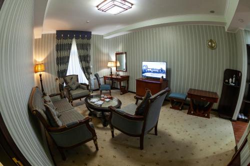 a living room with a couch and chairs and a television at Zargaron Plaza in Bukhara