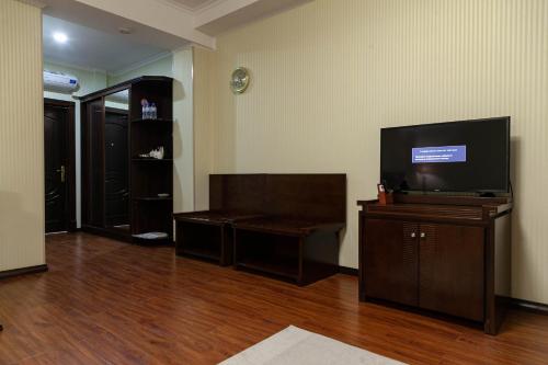 a living room with a flat screen tv on a wooden floor at Zargaron Plaza in Bukhara