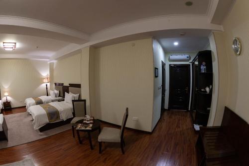 a hotel room with a bed and a table and a chair at Zargaron Plaza in Bukhara