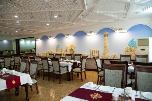 a restaurant with tables and chairs in a room at Zargaron Plaza in Bukhara