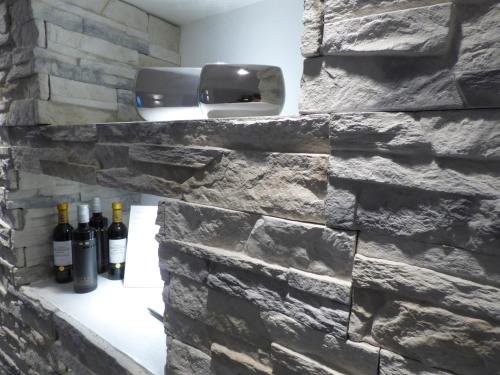 eine Steinwand mit Weinflaschen auf einem Regal in der Unterkunft EWERTS Hotel in Netphen