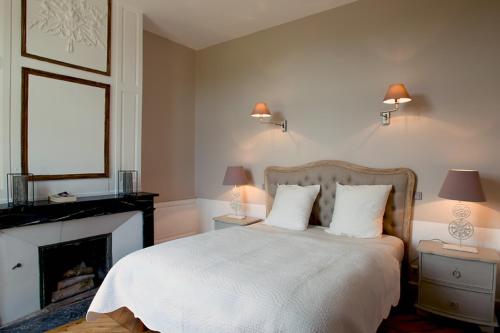 a bedroom with a white bed and a fireplace at Château de Perreux, The Originals Collection in Amboise
