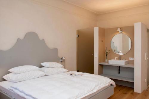 una camera da letto con un letto con specchio e lavandino di Der Pfarrhof a Hartberg