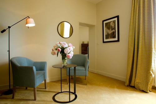 a room with two chairs and a table with a vase of flowers at Château de Perreux, The Originals Collection in Amboise