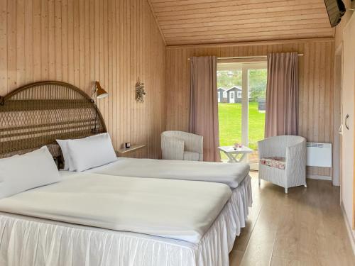 a bedroom with two beds and a large window at Hotel Strandgaarden in Vesterø Havn