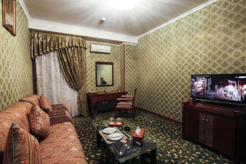 a living room with a couch and a television at Zargaron Plaza in Bukhara