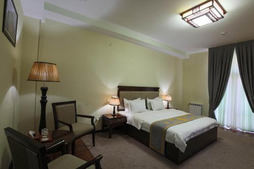 a hotel room with a bed and a chair at Zargaron Plaza in Bukhara