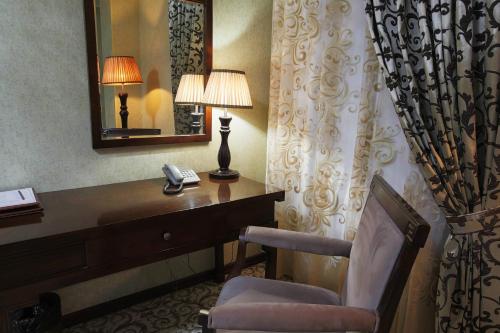 a hotel room with a desk and a chair and a mirror at Zargaron Plaza in Bukhara