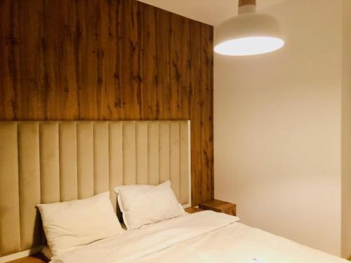 Schlafzimmer mit einem weißen Bett mit einem Kopfteil aus Holz in der Unterkunft Joy City Stay Vivalia 7B-13 in Timişoara