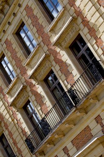 a tall brick building with windows and a balcony at Château de Perreux, The Originals Collection in Amboise