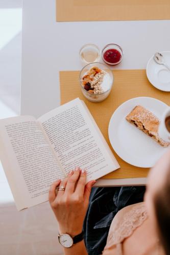 a woman sitting at a table reading a book at Hotel Venezia in Trento