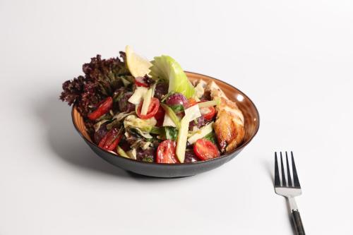 a salad in a bowl next to a fork at شقق الماسة التاج للشقق الفندقية in Hail