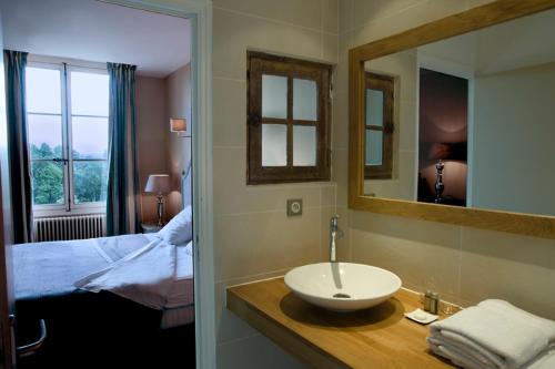 a bathroom with a sink and a bed and a mirror at Château de Perreux, The Originals Collection in Amboise