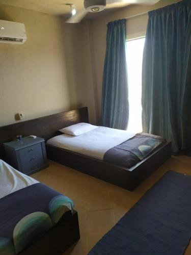 um quarto com 2 camas e uma janela com cortinas azuis em Cozy Villa Venice Ain Sokhna em Ain Sokhna