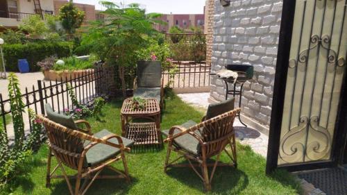 a yard with two chairs and a table and a grill at Cozy Villa Venice Ain Sokhna in Ain Sokhna