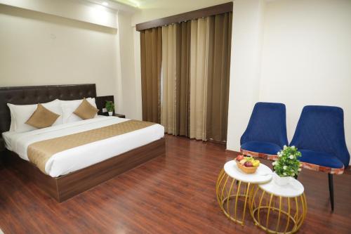 a hotel room with a bed and two blue chairs at Comfort Inn Karnal in Taraori