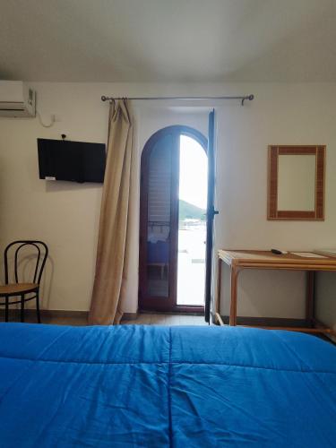 a bedroom with a blue bed and a sliding glass door at Hotel Faraglione in Vulcano