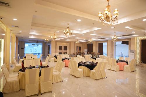 a banquet hall with white chairs and tables and chandeliers at Comfort Inn Karnal in Taraori