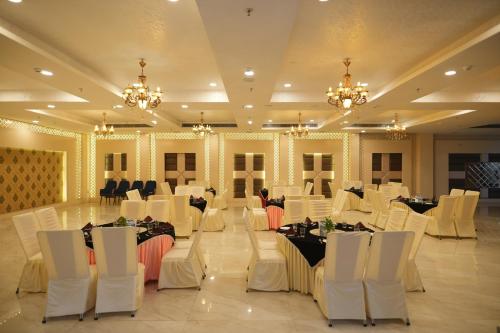 a banquet hall with white tables and chairs and chandeliers at Comfort Inn Karnal in Taraori