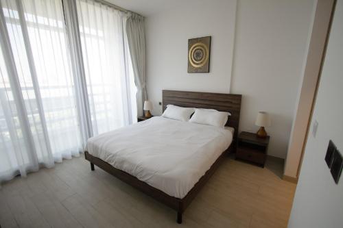 a bedroom with a bed with white sheets and windows at 40 Minutes drive to Burj Khalifa in Sharjah