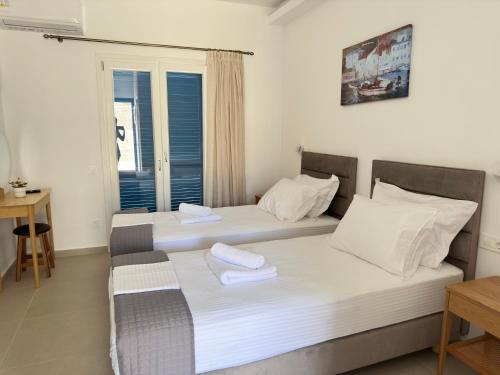 two twin beds in a room with a window at COSMOS Studios Iraklia in Áyios Yeóryios