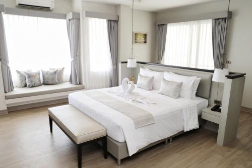 a bedroom with a large white bed and two windows at THE NAVY HOUSE HOTEL in Sattahip