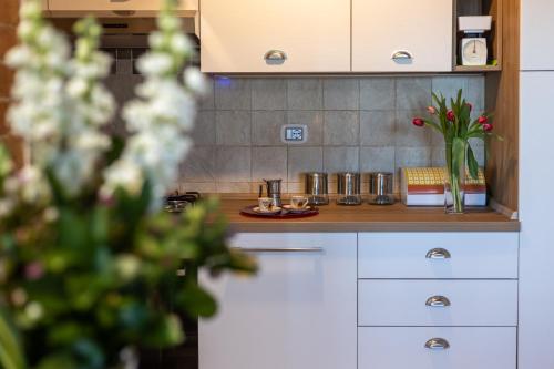 a kitchen with white cabinets and a vase of flowers at Casa Ernesto - porzione di colonica in Monteriggioni