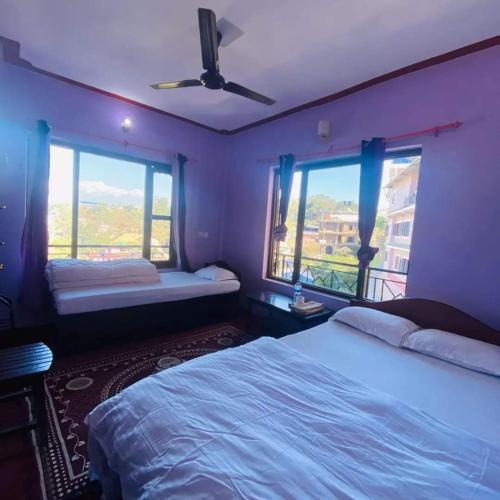 a bedroom with two beds and a ceiling fan at Himchuli Guest House in Bandīpur