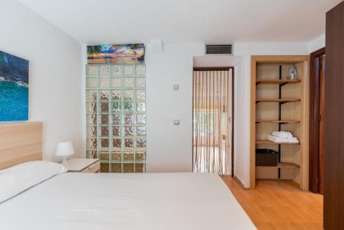 1 dormitorio con cama blanca y ventana en Holi-Rent Esperanza, en Sevilla