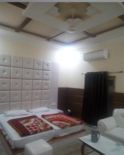 a room with a bed and a couch and a ceiling at Shri Ram Hotel in Ayodhya