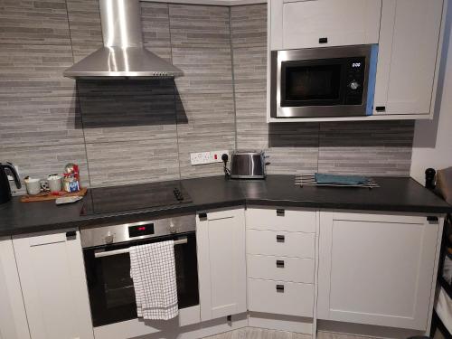 uma cozinha com armários brancos e um micro-ondas em Flat 6 Corner House em Doncaster